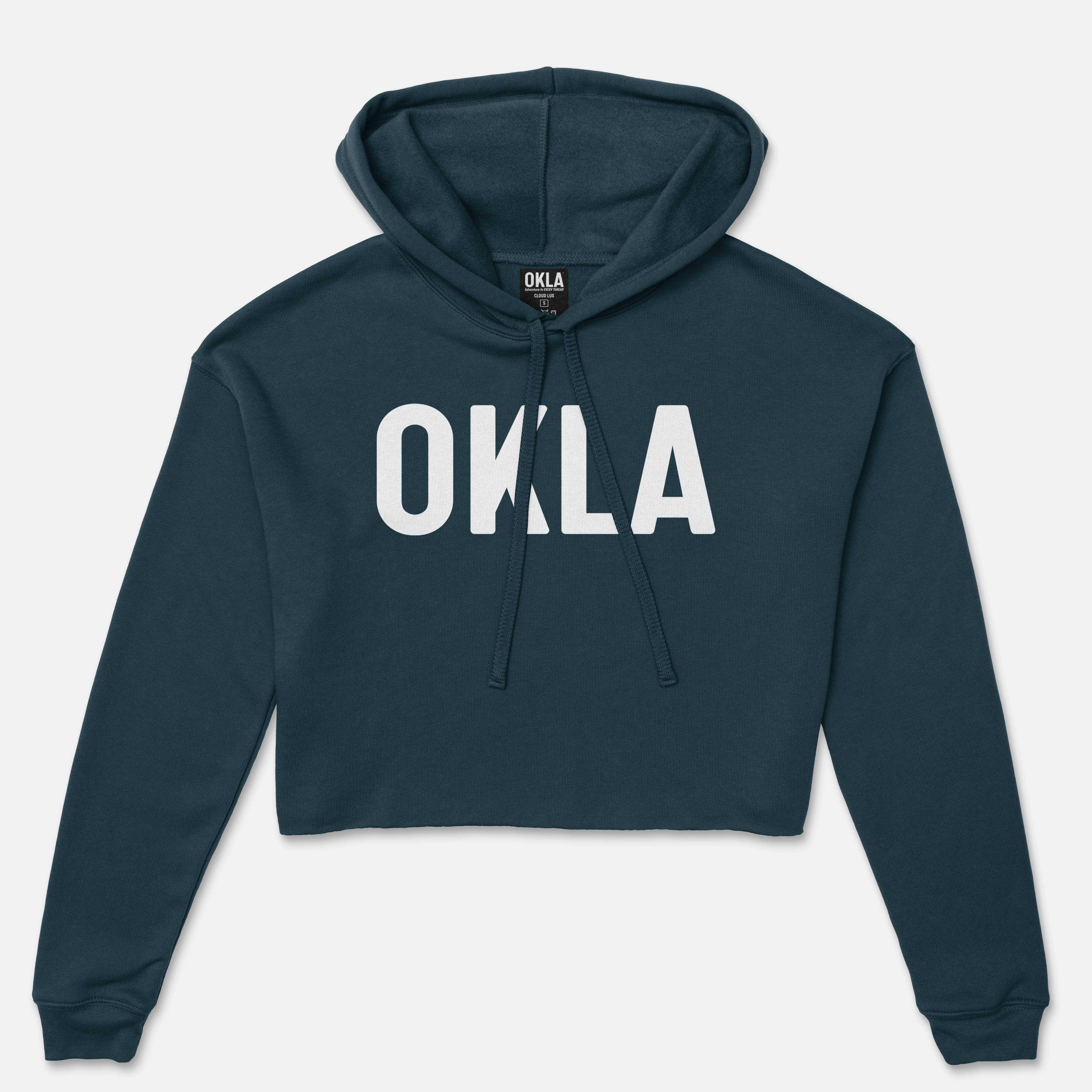 The OKLA Original Crop Hoodie, colored in dark teal with "OKLA" boldly printed in white on the front, is ideal for a fashion magazine feature. It combines style with comfort through its adjustable drawstring at the neckline.