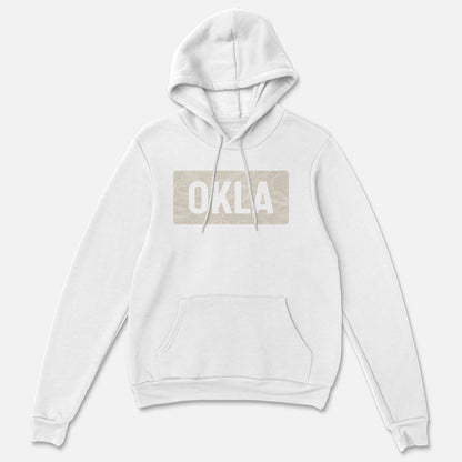 Embrace the adventure and comfort of the OKLA Navigator BOLD Hoodie, a white hoodie made from recycled cotton. It includes a front pocket and drawstrings, while the chest showcases a beige rectangular patch with "OKLA" in bold white capitals against a simple light gray backdrop.