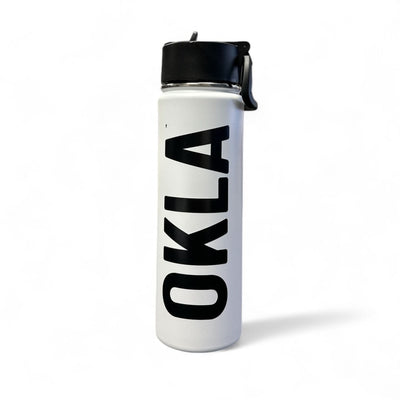 The OKLA - Travel Thermos 22oz is a sleek, stainless steel white water bottle with a leak-proof black lid. It showcases the word "OKLA" in bold black letters vertically and stands upright on a white background, ready for any adventure.