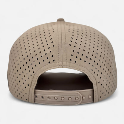 The image displays the back view of the OKLA Navigator Hat, a beige perforated baseball cap equipped with an adjustable snapback strap and sweat-wicking technology. The cap's small hole pattern offers ventilation, combining style and functionality.