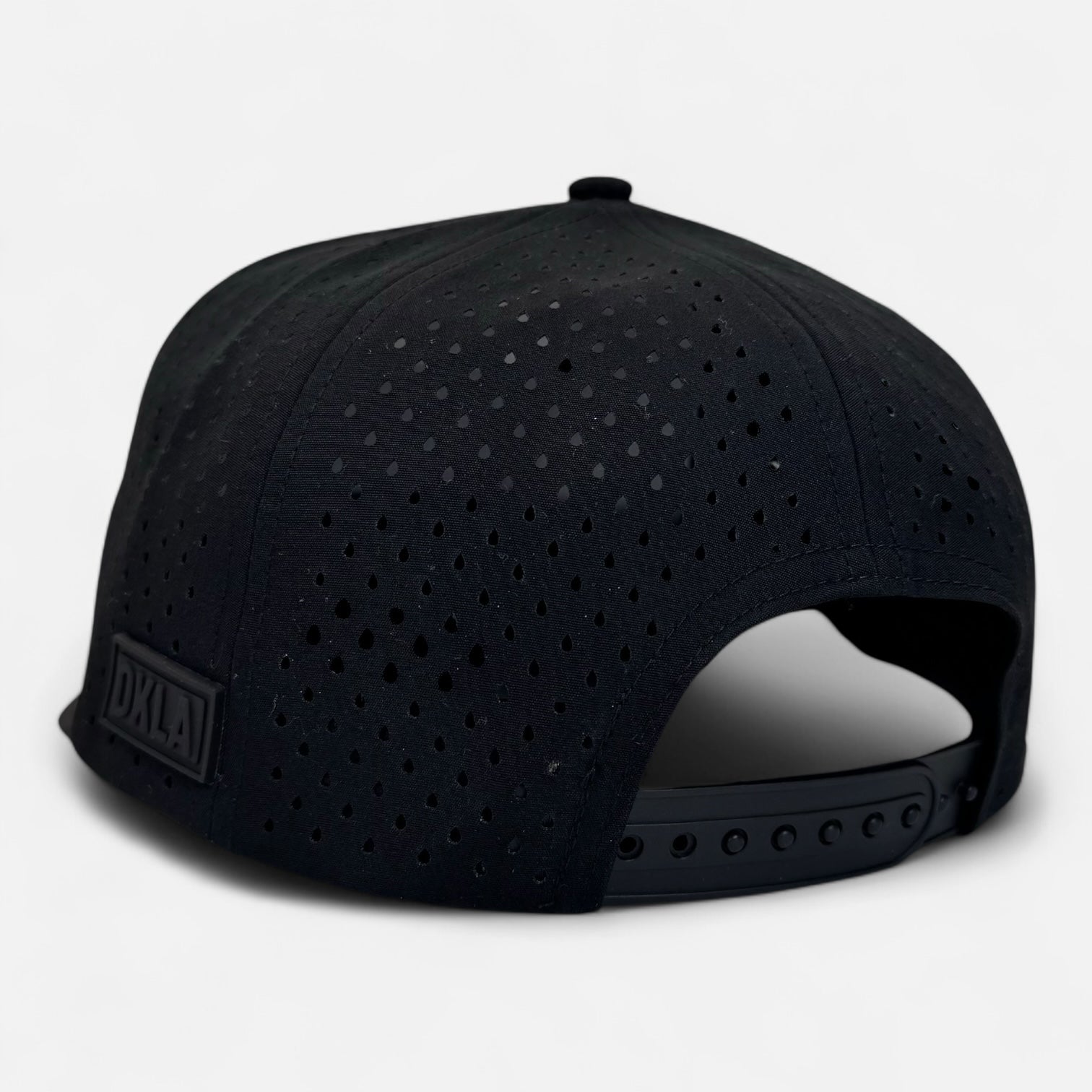 Introducing the OKLA Navigator Hat: a black baseball cap with a perforated design and sweat-wicking technology. It features an adjustable strap at the back and is adorned with a small DXLA label set against a plain white background.