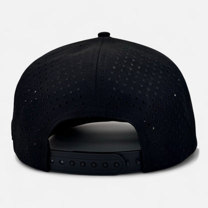 The image displays the reverse side of an OKLA Navigator Hat in black, highlighting its perforated design and adjustable snapback closure, complemented by sweat-wicking technology.