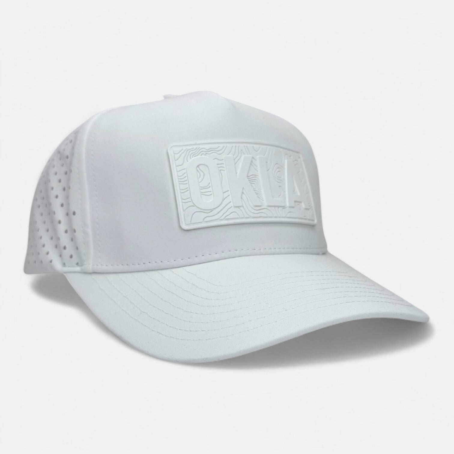 The OKLA Navigator Hat is a light mint green baseball cap that features a vintage-inspired 3D patch with "OKLA" on the front. Designed with sweat-wicking technology, it also includes perforated sides for ventilation and a curved brim, all on an understated white backdrop.