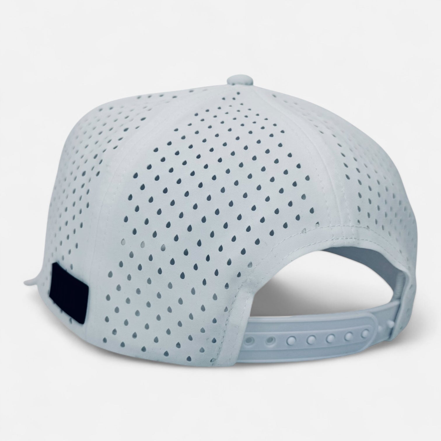 The OKLA Navigator Hat, shown in light gray with a back view, boasts a breathable design with sweat-wicking technology. It features perforations for improved ventilation, a snapback closure for adjustable comfort, and a black rectangular label on the side. The hat pays homage to vintage style with its distinctive 3D patch detail.