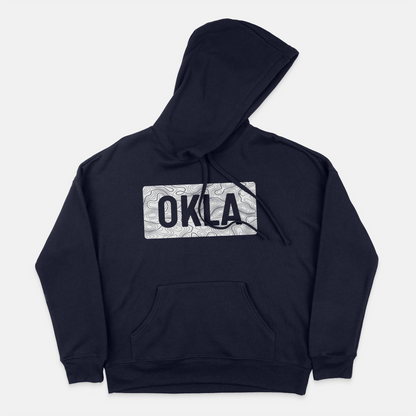 The OKLA Navigator BOLD Hoodie is a navy hoodie crafted from recycled cotton. It showcases a patterned rectangular design on the chest with the letters OKLA, offering a comfortable unisex fit. The hoodie features a front pocket and an adjustable drawstring hood for added convenience.