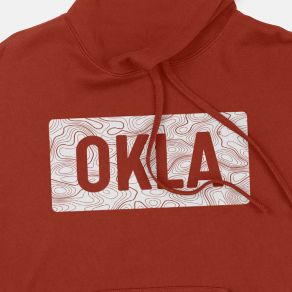 Check out the OKLA Navigator BOLD Hoodie, designed with a cozy unisex fit. It boasts a striking red color with "OKLA" prominently displayed in white within an exclusive topographic map design. Made from recycled cotton, this hoodie also features a drawstring hood for enhanced style and comfort.