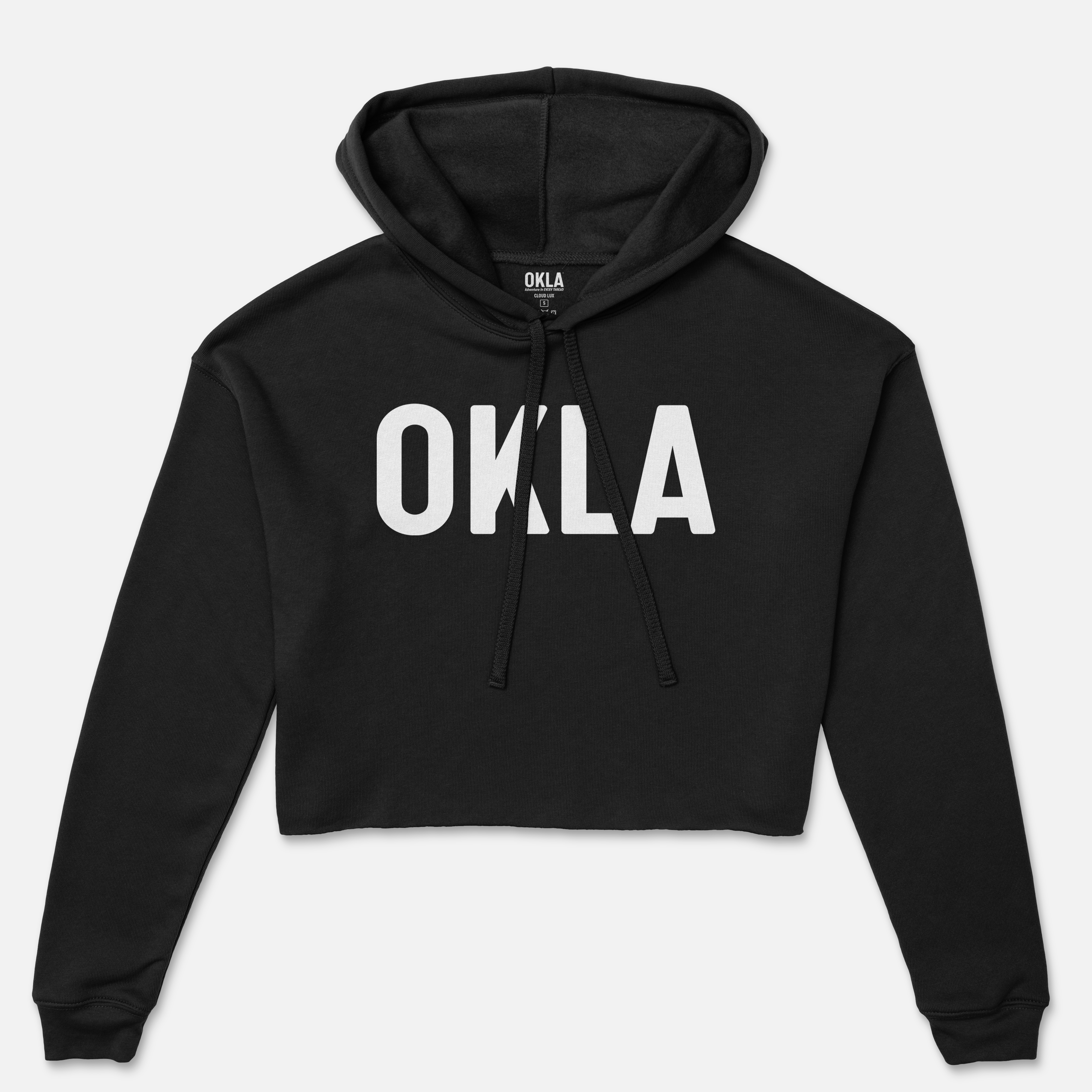 The OKLA Original Crop Hoodie, a black fleece design with a hood and drawstrings, showcases bold white lettering spelling "OKLA" on the front. This fashionable addition to your magazine wardrobe is presented against a plain white background.