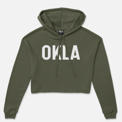 Introducing the OKLA Original Crop Hoodie, a stylish green fleece design boldly displaying the word OKLA in white letters across the front. This hoodie, complete with an attached hood and drawstrings, is perfect for making a statement and looks like it has come straight out of a fashion magazine.