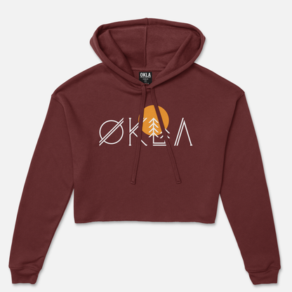 The OKLA Native Crop Hoodie is a maroon piece featuring a modern front design that creatively combines the word OKLA with a tree and sun graphic. Made from cozy fleece, it offers both style and comfort in one minimalist design.