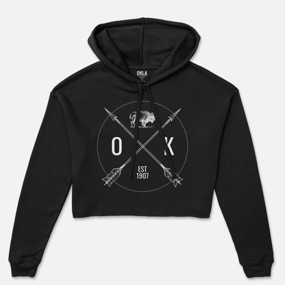 OKLA Shield - Crop Hoodie: A fashion-forward black fleece crop hoodie featuring a graphic design of a bear, crossed arrows, and the letters "O K," with "EST 1907" in white.