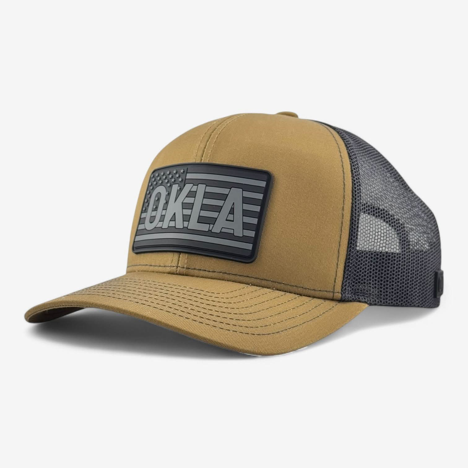 The OKLA Freedom Trucker Hat is a hunter brown and black mesh cap with a vintage-inspired 3D patch showcasing an American flag and the text "OKLA" on the front. It features sweat-wicking technology, a curved brim, and an adjustable back for both comfort and style.