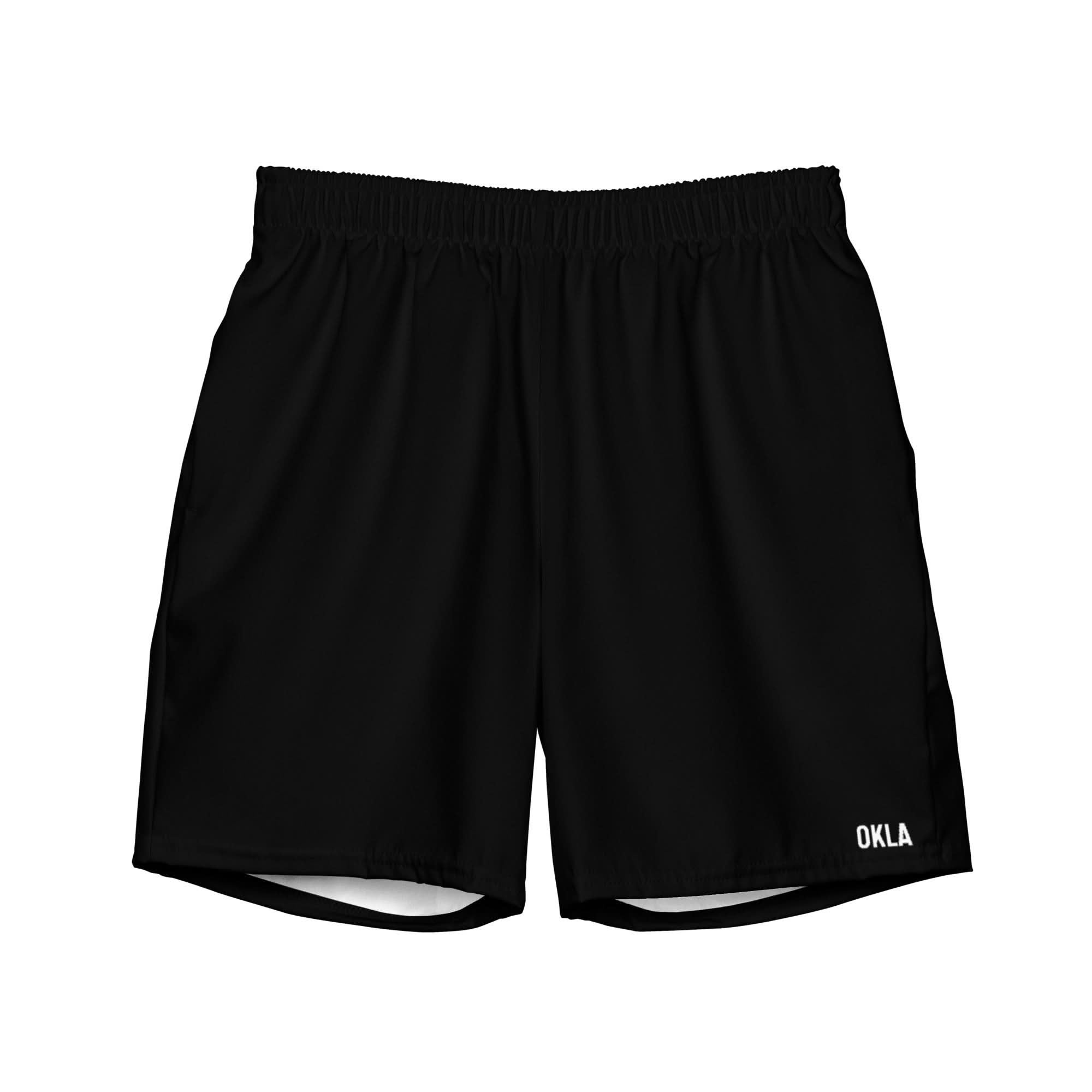 These OKLA Boardshorts are black athletic shorts made with a quick-drying, four-way stretch fabric and an elastic waistband. Featuring "OKLA" printed in white on the bottom right corner, they provide both style and flexibility for active days.