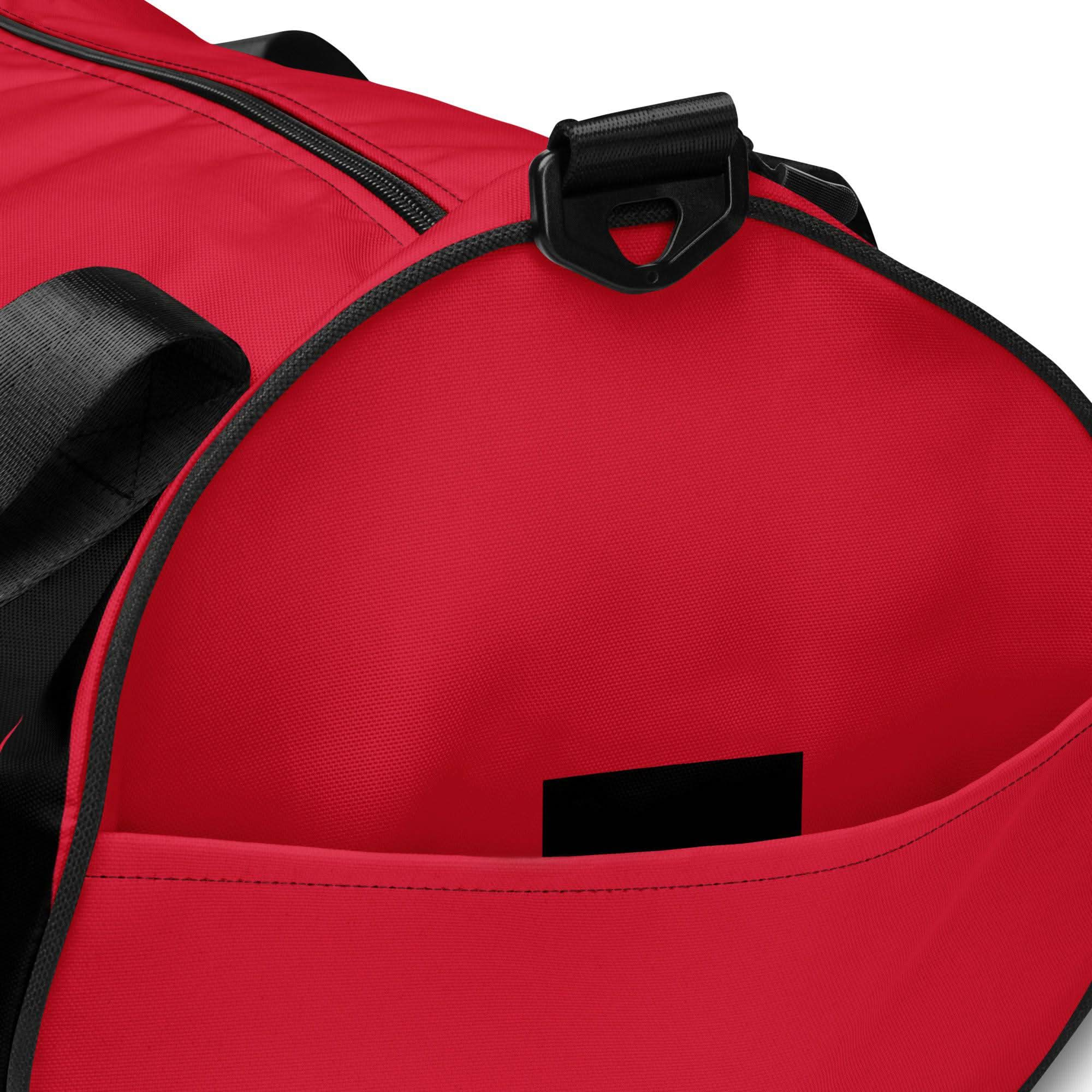 Close-up of The OKLA - Gym Bag Red Series, showcasing a black zipper and handle. The opening reveals a roomy interior made from durable fabric. Its water-resistant material guarantees longevity, and the edge of the pocket displays an attached black tag.